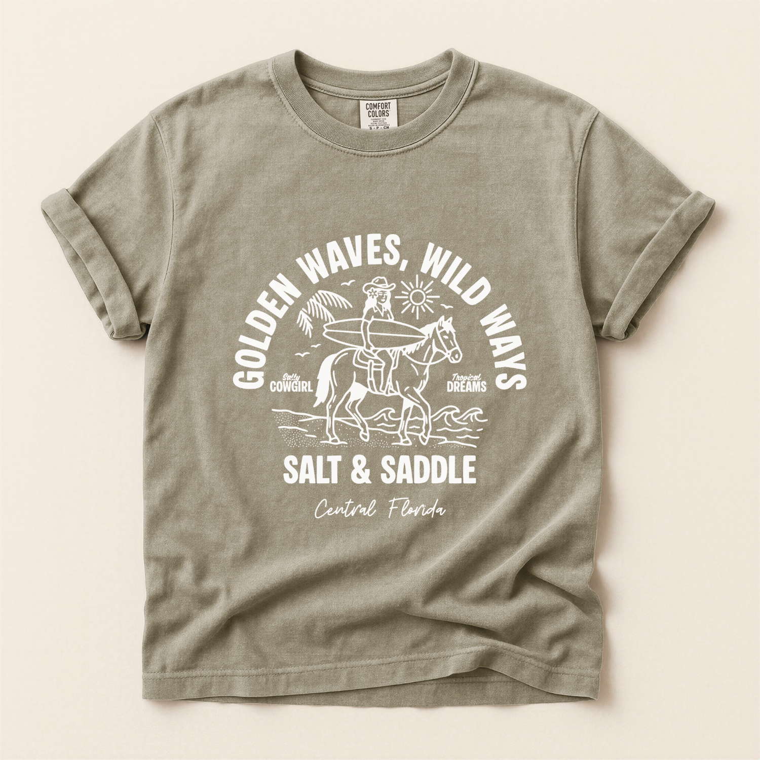 Vintage grey t-shirt with a white graphic of a cowgirl riding a horse along the beach. The girl is holding a surfboard. The text says salt and saddle, Central Florida. Coastal Cowgirl theme.