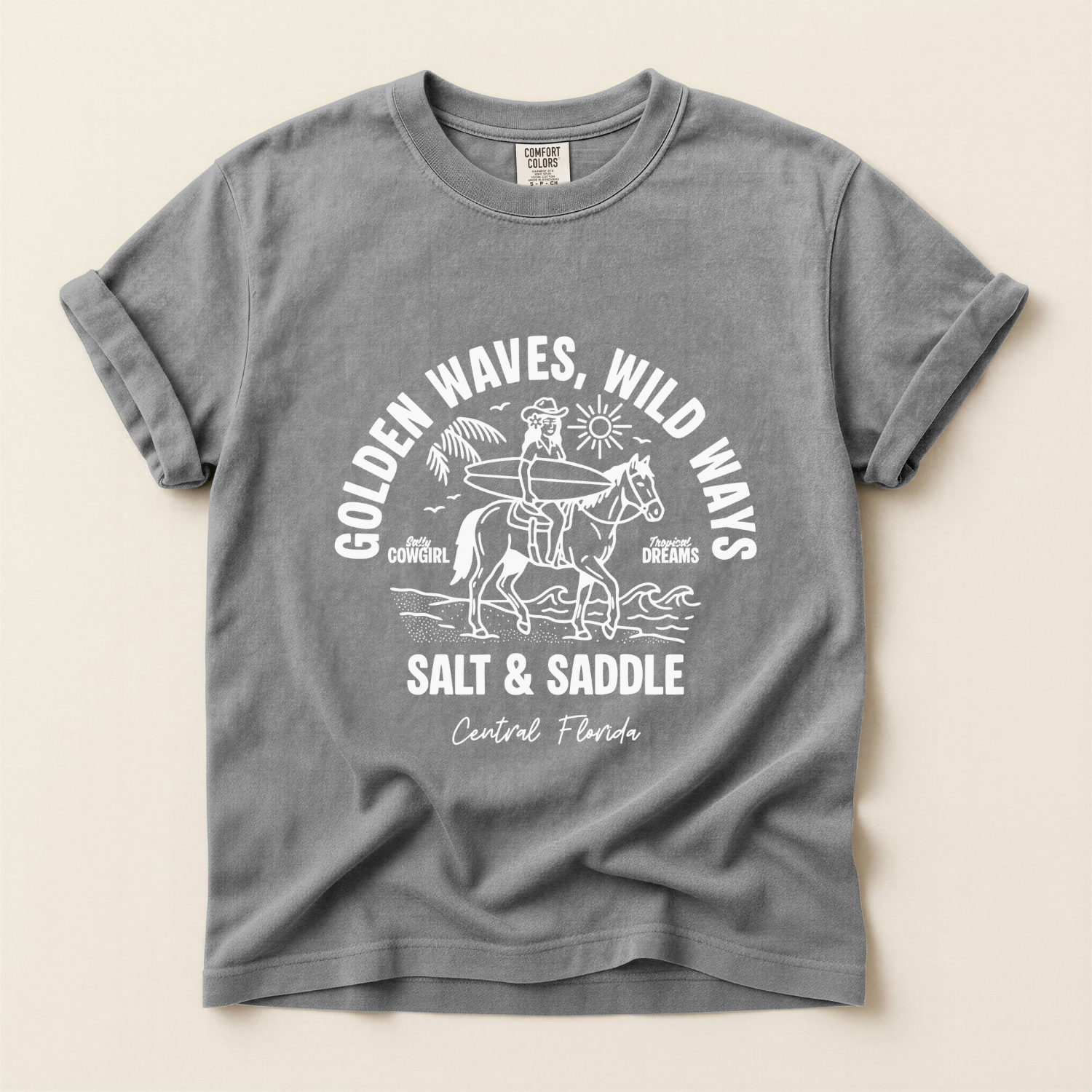 t-shirt with a white graphic of a cowgirl riding a horse along the beach. The girl is holding a surfboard. The text says salt and saddle, Central Florida. Coastal Cowgirl theme.