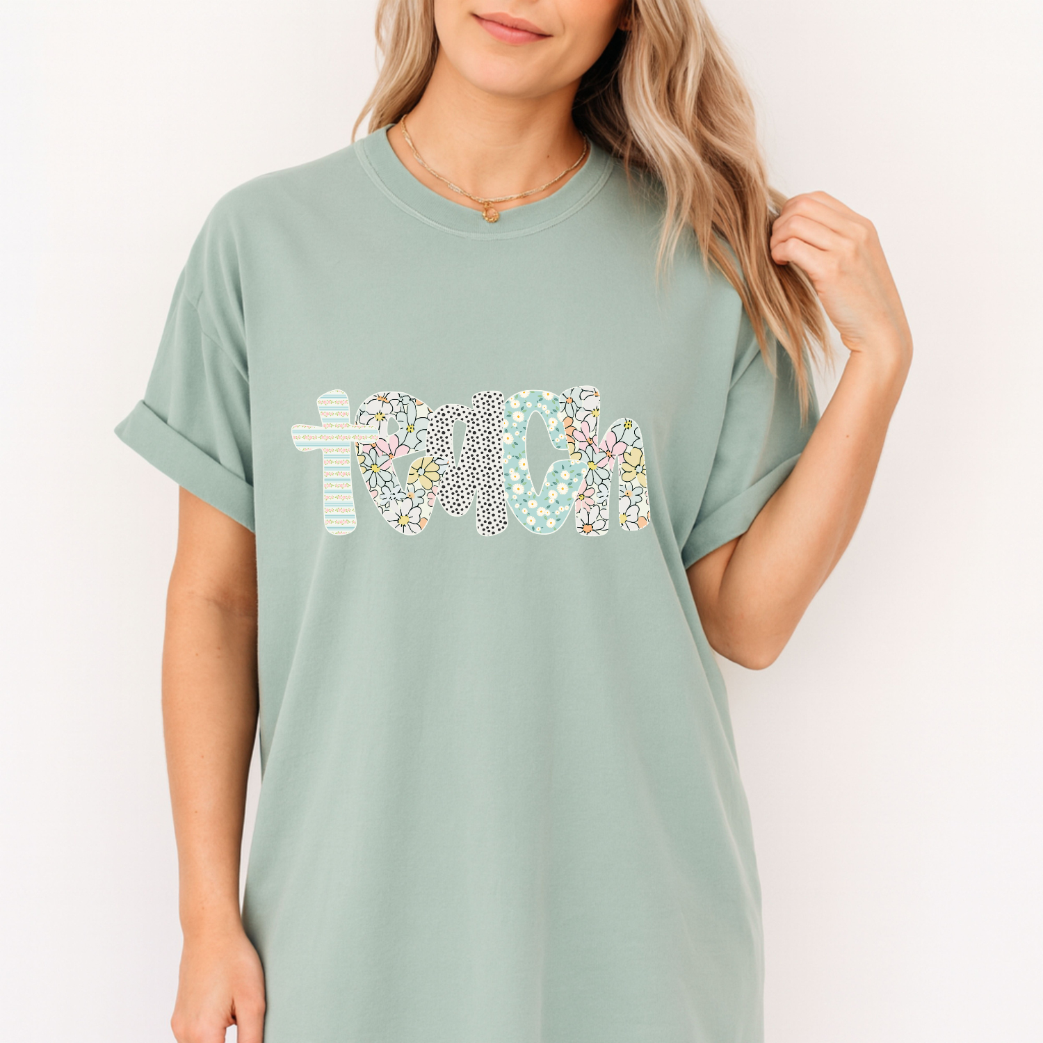 Person wearing a light green t-shirt with floral text design on a plain background