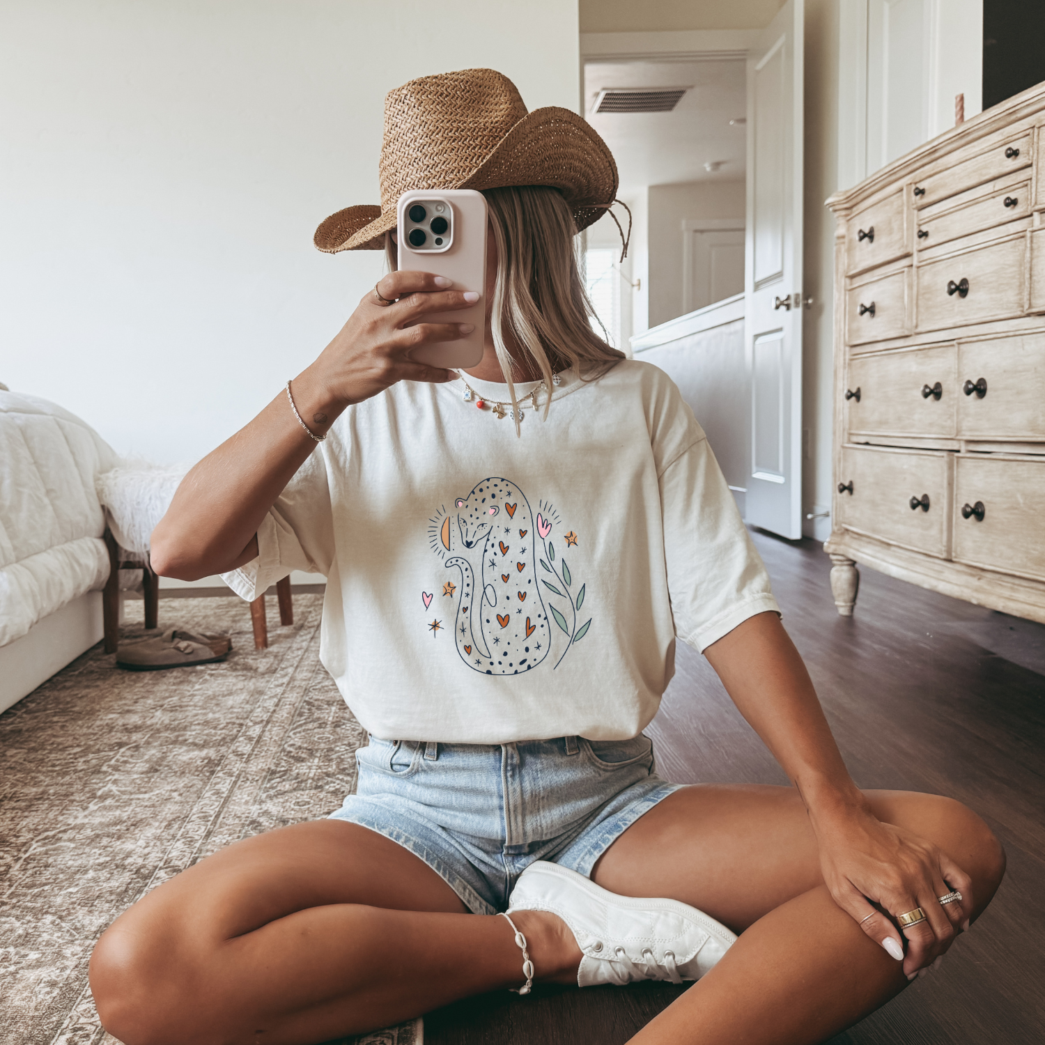 Girl with straw hat and ivory colored tee with a cute hand drawn boho illustration of a leopard