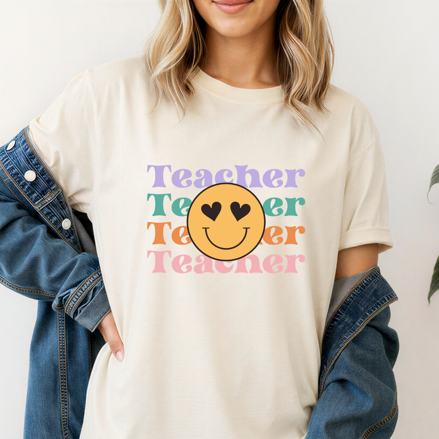 Person wearing a cream t-shirt with 'Teacher' text and smiley face design.