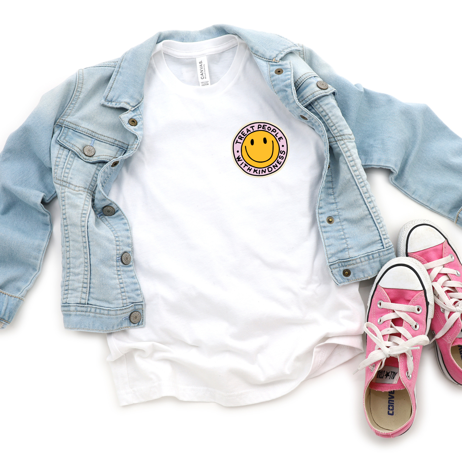 White t-shirt with a smiley face graphic, light blue denim jacket, and pink sneakers on a white background