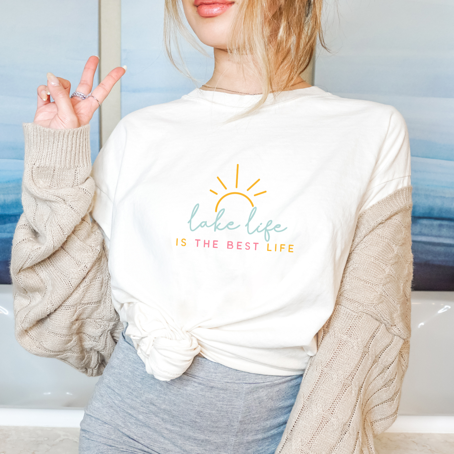 Person wearing a white sweatshirt with 'Lake Life is the Best Life' text and sun graphic.