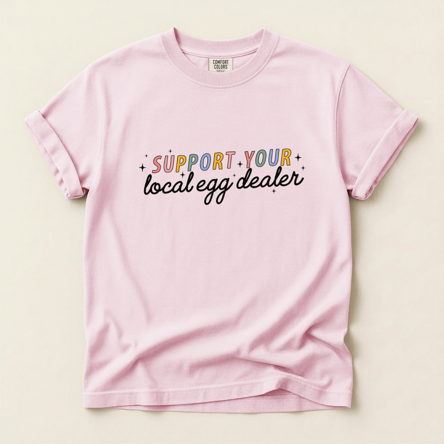 Pink t-shirt with colorful text 'Support your local egg dealer' for homestead mamas and chicken farmers