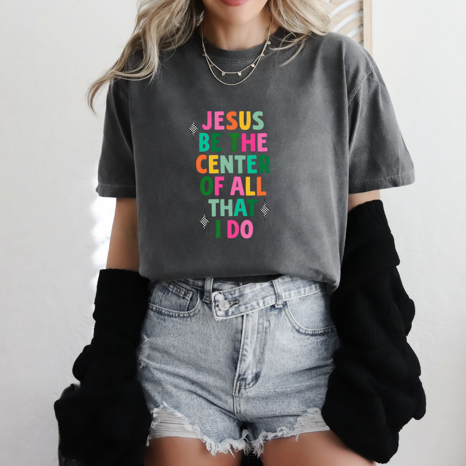 Person wearing a gray t-shirt with colorful text that says "Jesus be the center of all I do" in colorful letters