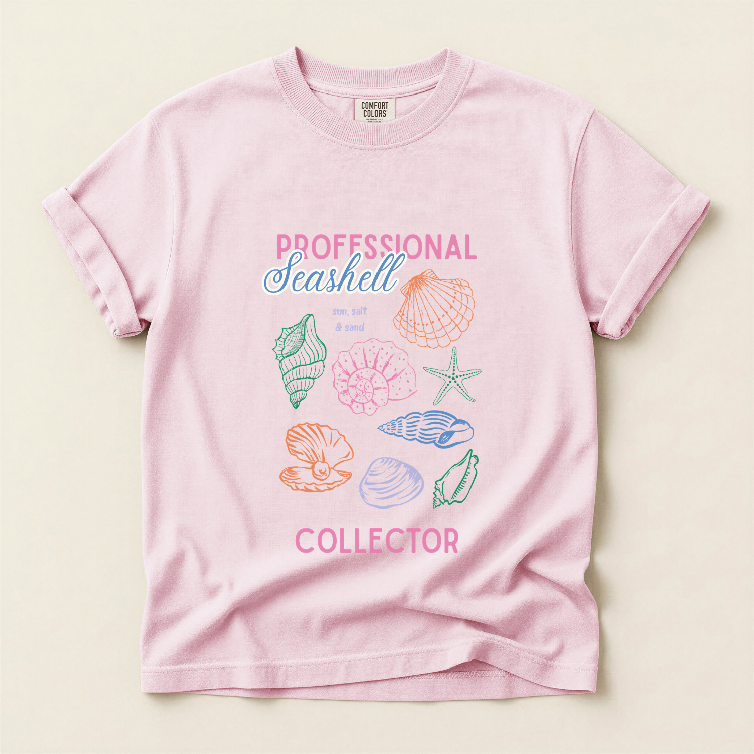 pink comfort colors ivory tee with colorful seashells and the words "professional seashell collector"