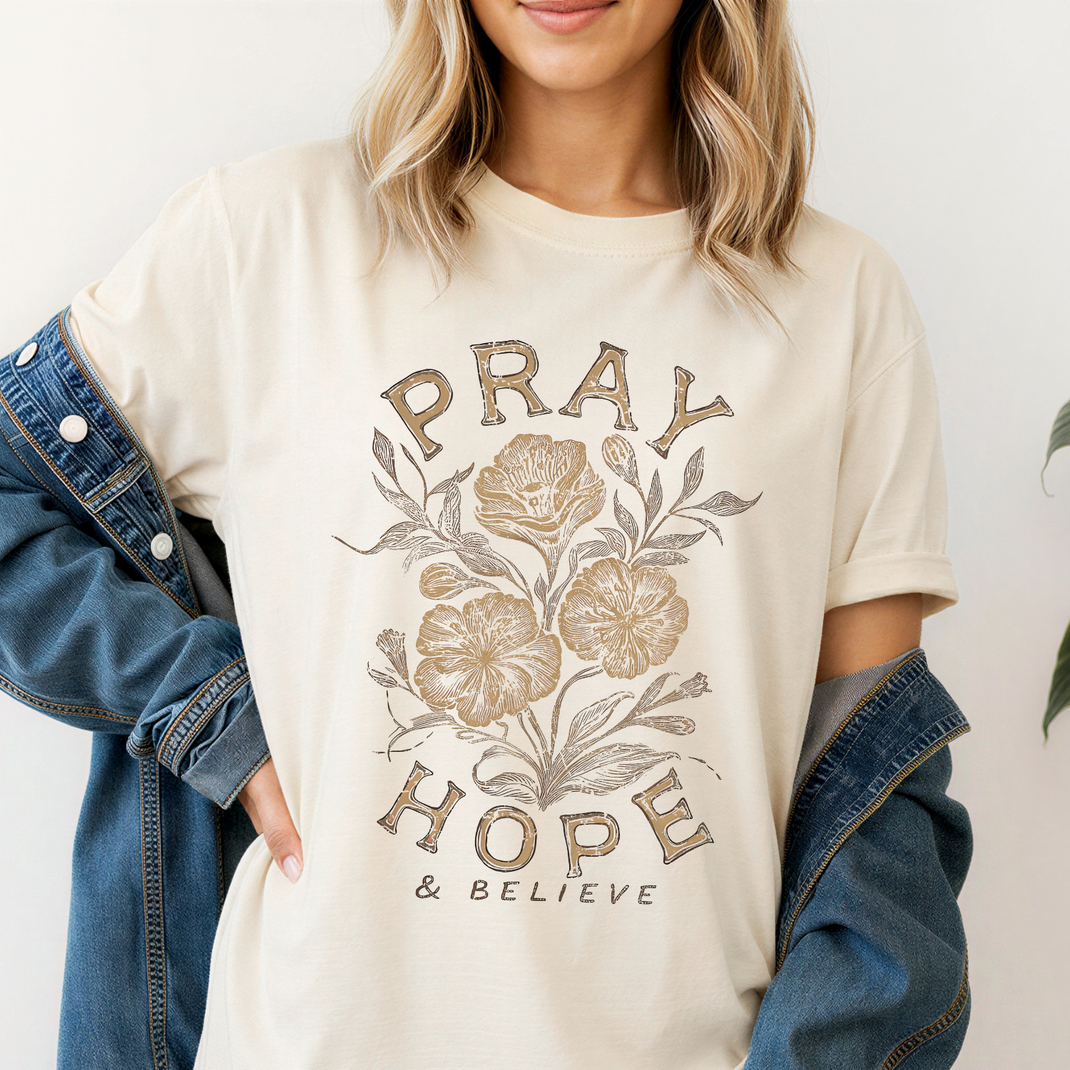 Ivory comfort colors tee on model - tee features florals in neutral brown and tan tones with the text "pray hope and believe"