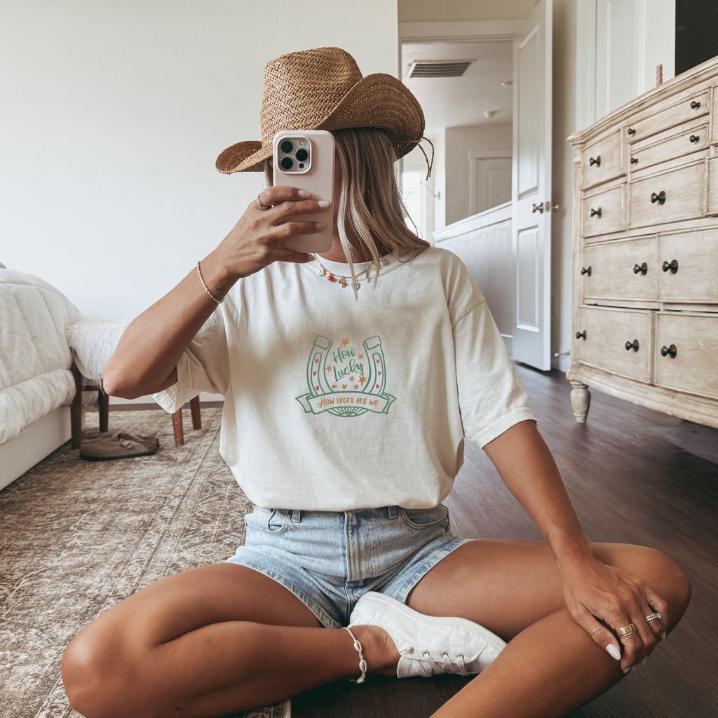 Western styled outfit with off white shirt that has a horseshoe with text that reads "how lucky"