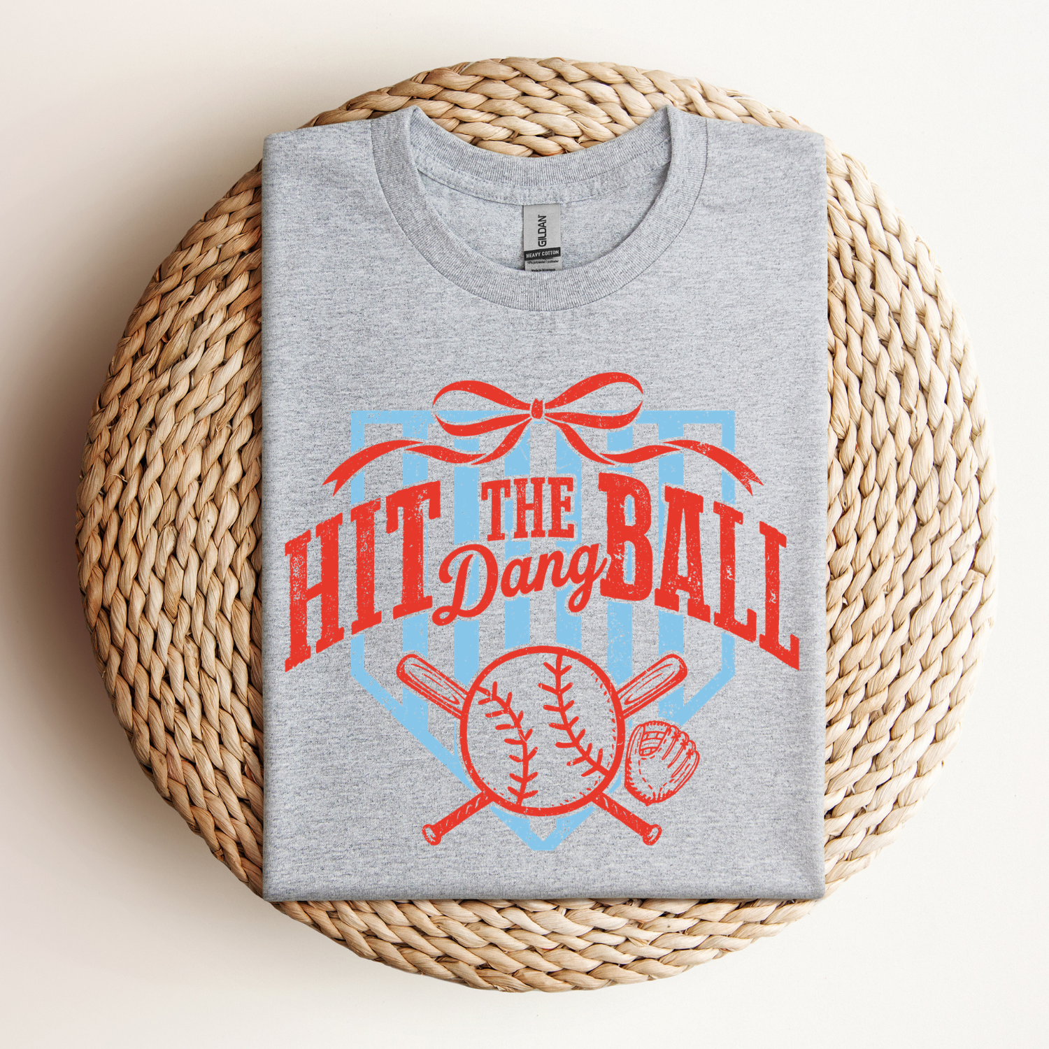 Preppy baseball t-shirt design with text that reads "hit the dang ball" and is bright red. There is a red bow and baseball mit and bats